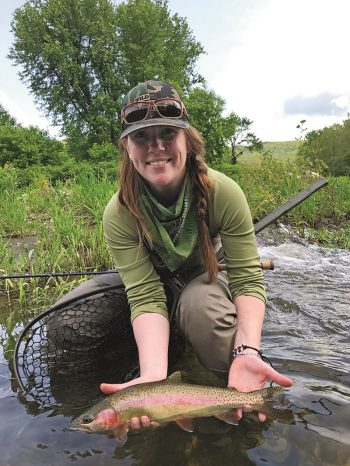 Young woman fly fishes on a river in Central Vermont.