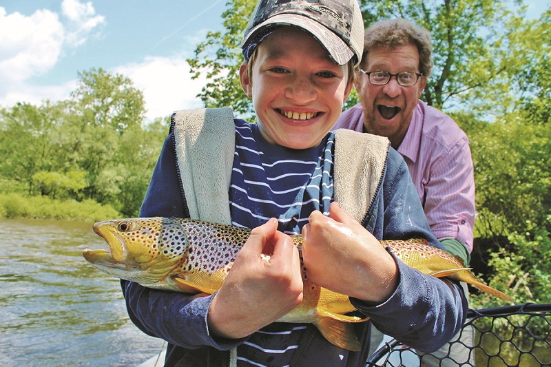 Young woman fly fishes on a river in Central Vermont.