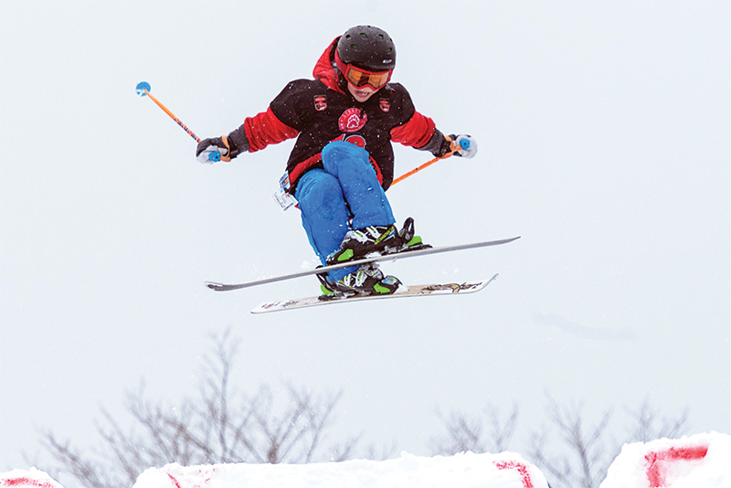 young boy on skis going off a jump