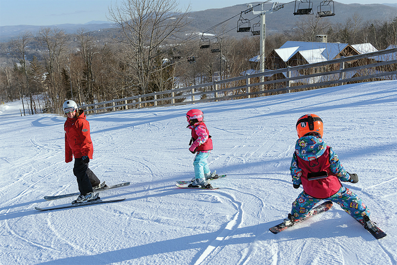 instructor teaching small kids to ski