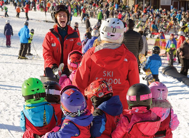 ski instructor laughing and leading a group of kids