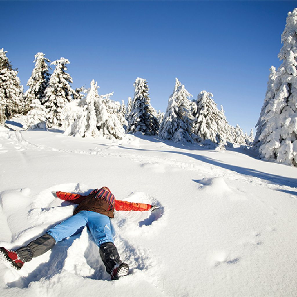 girl making snow angel in snow