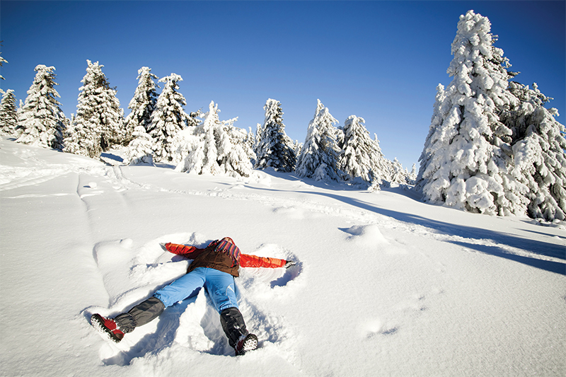 girl making snow angel in snow